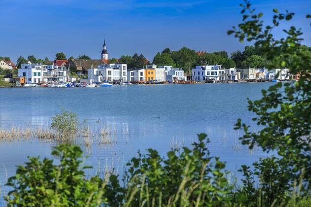 Lagune Kahnsdorf im Leipziger Seenland DEU Sachsen Kahnsdorf Â +49171 6254657 Am Südwestufer des aus dem Restloch des Tagebaus Witznitz II hervorgegangenen, rund 565 Hektar großen Hainer See entsteht in der Lagune Kahnsdorf ein bislang in der mitteldeutschen Bergbaufolgelandschaft einzigartiges städtebauliches Ensemble. Die Ferienhausanlage am östlichen Ortsrand von Kahnsdorf besteht aus etlichen Ferienhäusern mit Bootsgaragen und Bootsanlegern, die eine architektonisch gelungene Verbindung zwischen Land- und Wasserfläche schaffen. Der größte Teil der Fläche für die Ferienhaussiedlung war bereits 2004 von der LMBV veräußert worden. Nachdem ein großer Teil der Ferienhäuser errichtet und verkauft bzw. verpachtet ist, entstand in unmittelbarer Nachbarschaft ebenfalls direkt am See ein Hotel mit 18 Ferienwohnungen. Das Leipziger Neuseenland verändert sich immer mehr in eine