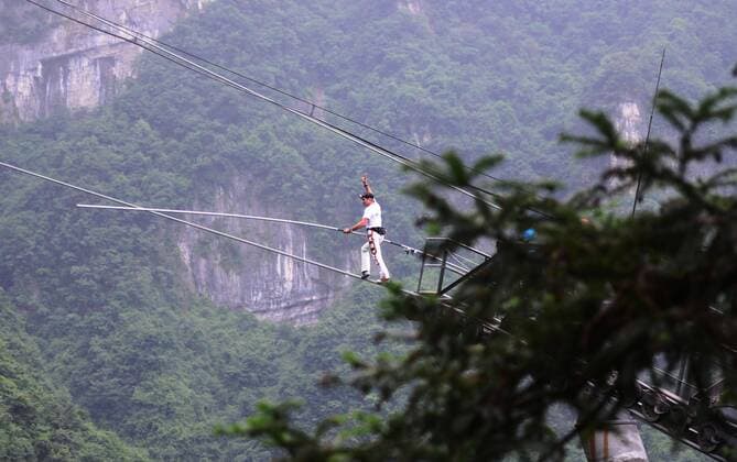 ZHANGJIAJIE, CHINA - JUNE 28: (CHINA OUT) Freddy Nock, known as Europe s King of the High Wire , walks on the Tianmen Mountain Cableway without any protective measures on June 28, 2014 in Zhangjiajie, Hunan Province of China. Freddy Nock, who is a world record holder of various events and known as Europe s King of the High Wire , once again took on the challenge of walking on Asia s longest and most dangerous cable, the Tianmen Mountain Cableway, without any protective measures. After walking 420 m, he gave up because the slope was too steep and his feet were too slippery. In 2010, Nock did the same challenge at Tianmen Mountain Cableway. He walked for about 200 m before giving up due to severe rolling and shaking of the cable beneath his feet.  CFP454399261