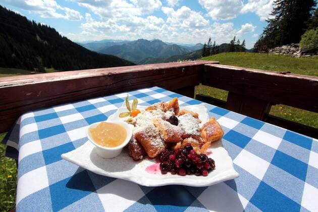 Teller mit Kaiserschmarrn und Kompott sowie Obst steht auf einem in den Landesfarben Bayern s gedeckten Tisch in den bayerischen Alpen, BAyern, Deutschland