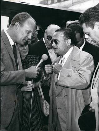 Jul. 07, 1957 - Victor Riesel visits Germany The American journalists Victor Riesel (43) who had been attacked by a criminal with sulphuric acid on April 5, 1956 in New York and has thus lost his eye-sight, arrived for a three-week visit in the Federal Republic of Germany on July 14, 1957 by invitation of the German Press Office. Riesel became well-known through his campaign against the gangsters in the unions of the USA. After paying a several-day visit to Bonn where he will be received on July 16, 1957 by the German Chancellor Konrad Adenauer, Riesel will make a trip through the Federal Republic of Germany and collect date on the German re-union and the communist infiltration - as well as neo-fascist infiltration - of the workers. It is probable that he will also consult German eye-specialists. OPS;- Riesel (with dark glasses) during an interview by German journalists after his arrival  - ZUMAk09