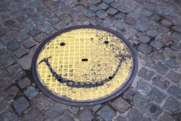 Kanaldeckel mit einem Smily Gesicht bemalt,