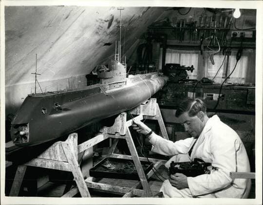 Nov. 11, 1959 - Ten Foot Working Model of a Submarine Built in a Bedroom... It Will Actually Fire Real Missiles. A ten foot long model of a submarine has been built in the attic bedroom of a 38 year old Ministry of supply worker - Mr. David Ashton of Sevenoaks, Kent, at a cost of ,000... Named Olympus it will be capable of firing missiles and torpedoes while submerged - being operated by remote control. The model was started three years ago - weighs 200 lbs and is capable of diving 15 feet... It will be fitted with navigational lights and Aldis lamps which will winks out Morse signals - and Mr. Ashton hopes to navigate it from Westminster to Calais in a few months time. An underwater movie camera can be fitted to the deck to film it course. The missiles will be the equivalent of the American Polaris rockets with a range of 300 yards. Photo Shows: Stocks in the attic... Mr. Ashton  - ZUMAk09