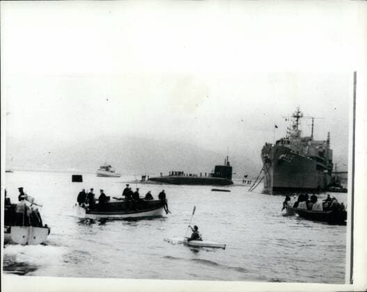 Mar. 03, 1961 - Demonstrations as Polaris submarine arrives in the holy loch The 6700 ton American Polaris submarine Patrick Henry - arrived in the holy look - firth of clyde today and tied up alongside the submarine depot ship Proteus , on arrival she was cheered by the Royal Navy and while she was making fast a lone demonstrator in a cance was dodging four navy launches with police on board. after 11 minutes the canoe was capsized and its occupant fished out of the water by naval frogmen. photo shows The scene as police launches close -in on the lone demonstrator - his cance was capsized - and he had to be fished out of the water by naval frogmen. The submarine cab be seen in rear.  - ZUMAk09