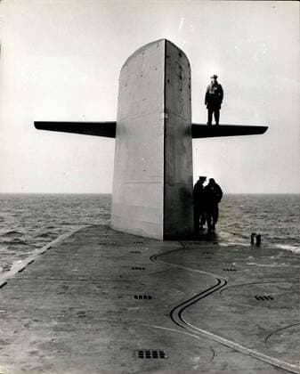 Feb. 28, 1963 - British Pressmen Visit U.S. Polaris Submarine.. Ethan Allen A number of pressmen made a visit today to see of the United States Polaris submarines moored near the Holy Loch - Scotland today - and were taken on a trip to sea. Ten officers and ninety men operate the ?50,000,000 vessel - which carries more destructive power that the total unleashed by both sides during the whole of the last war. Photo Shows:- Captain Lacy, Commanding Officer of the U.S.S. Polaris submarine Ethan Allen is seen standing on the top of the control tower s forward hydroplane today.  - ZUMAk09