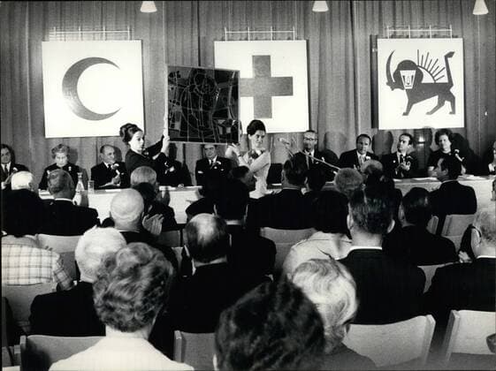 Apr. 04, 1969 - 50 years Red Cross League. The representatives of the 111 Nations member of the Red-Cross-League met in Geneva to celebrate the 50 years of existence of the organization. Swiss Federal Counsellor Willy Spuhler expressed the greetings of the Swiss government and suggested the realization in Geneva of a Henry Dunant Institute , commemorating so the founder of the Red Cross idea. OPS: The League receiving a present of the Swiss government in form of a precious glass painting. In the background the flags of the three major organizations member of the League: the Turkish Crescent , the Red Cross and the Red Lion  - ZUMAk09