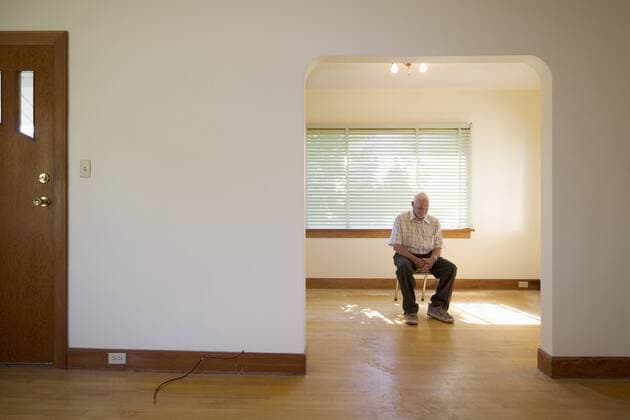 senior citizen (70-80 years old) sitting on chair in vacant house, Canada.  acp09533 RoyxOoms