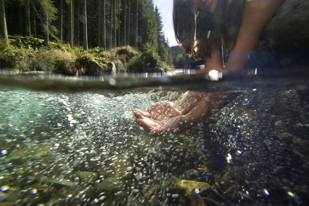 Maedchen haelt seine Haende in das klare Wasser eines Baches girl holding her hands in the water of a creek BLWS196779