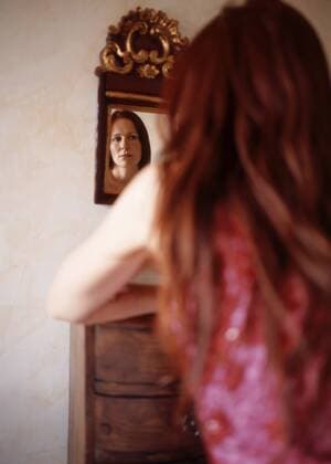 Red haired woman looking in mirror, rear view model released  PE00124