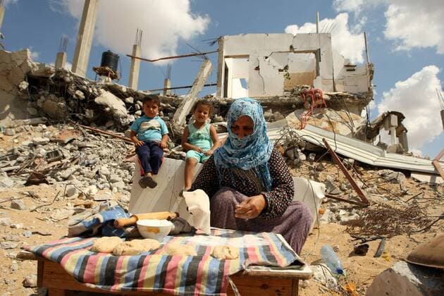 Palestinian woman Rowidh AL-najar , age 45, bake bread in the ruins of her house in Khan Younis that was destroyed by an Israeli air strike during a seven-week war with Gaza, in the southern Gaza Strip on September 21, 2014.Palestinian families made homeless during the latest war between Israel and Gaza, in Khan Yunis Khuzaa neighbourhood in the southern Gaza Strip. According to the UN agency for aid to Palestinian refugees (UNRWA), 65,000 homeless Palestinians are still sheltering in UN schools awaiting accommodation and thousands more have sought refuge with relatives.  GAZ2014092105