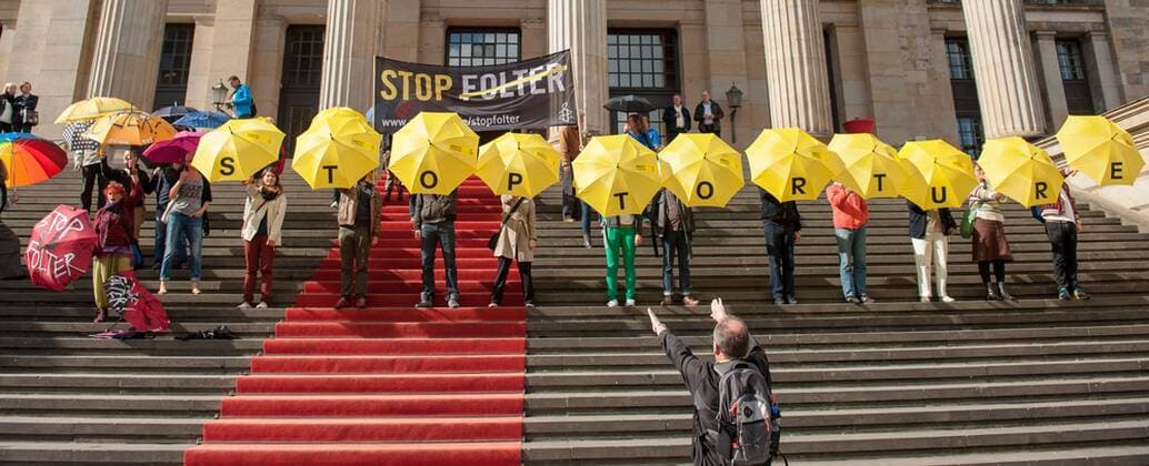 Berlin Politik Flashmob Amnesty International gegen Folter Im Rahmen der internationalen STOP FOLTER Kampagne veranstaltete die Menschenrechtsorganisation Amnesty International am Samstag den 27. September 2014 vor dem Konzerthaus am Gendarmenmarkt in Berlin-Mitte einen Flashmob. Mitglieder von Amnesty stellten sich auf die Treppe zum Konzerthaus und hielten gelbe Regenschirme auf denen Stop Torture stand. Unterstuetzer der Aktion kamen mit eigenen Regenschirmen und stellten sich dazu. 27.9.2014, Berlin
