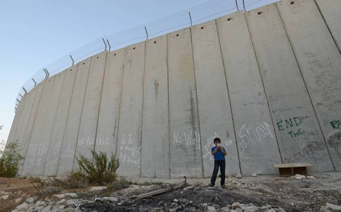 A Palestinian boy takes a photo with his cellphone in front of the Israeli separation wall in Abu Dis in the West Bank, September 29, 2014. Israeli Prime Minister Benjamin Netanyahu failed to mention a future Palestinian state in his address to the U.N. General Assembly today in New York.  JER2014092916