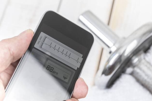 Hand holding smartphone with heart rate monitor showing cardiac arrhythmia model released Symbolfoto  DRF000993