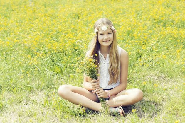 Portrait of a smiling girl sitting on a flower meadow wearing flowers model released Symbolfoto  GDF000373