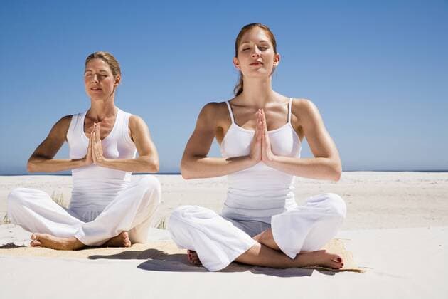 Two women exercising yoga on beach model released  WESTF04968