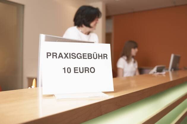 Germany, Hamburg, Women standing with text board in foreground at clinic model released property released  KNF001138