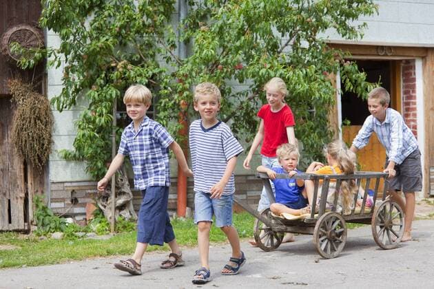 Germany, Bavaria, Group of children playing with hand cart in front of farmhouse model released property released  HSIYF000133