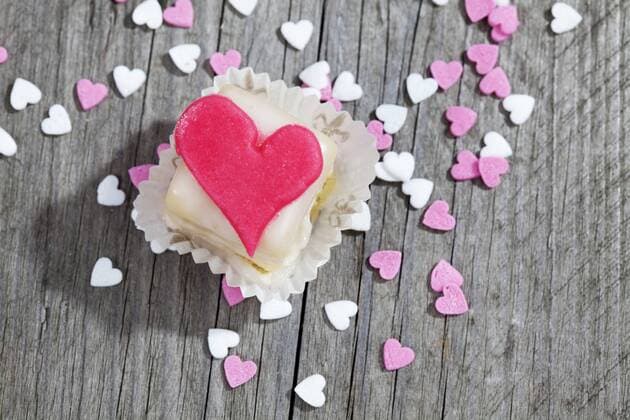 Petit four decorated with heart of marzipan on grey wood  CSF021128