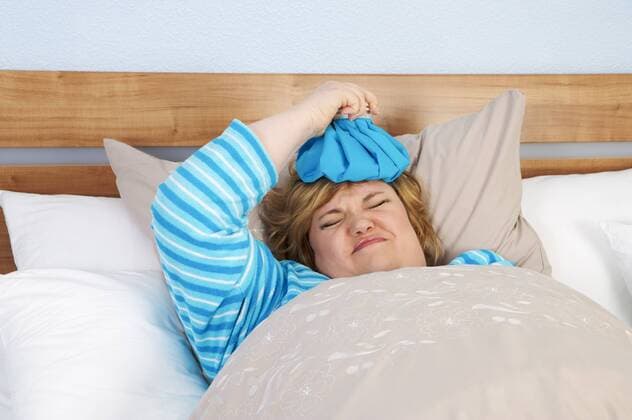 Germany, Mid-adult woman lying in bed with ice bag model released  ECF000575