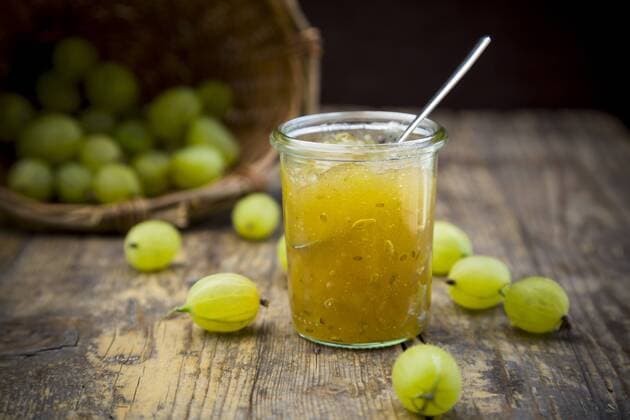 Jar of gooseberry jam, basket and organic gooseberries on dark wood  LVF001572