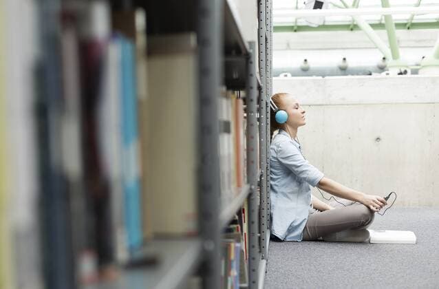 Student in a university library sitting on floor with headphones model released Symbolfoto property released  WESTF019617
