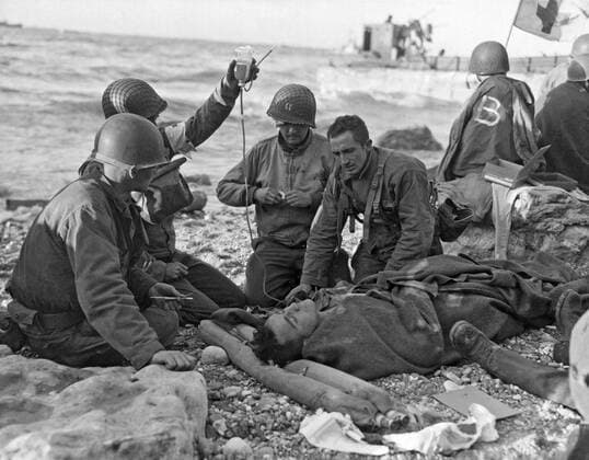 Normandy, France: June 7, 1944. Medics gving plasma on the beach to a wounded survivor of a sunken landing craft during the Normandy invasion. 990_16_4-WWII-US-E-DDay_1HR