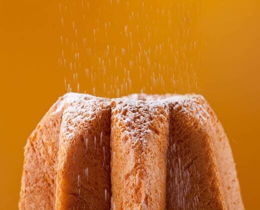 Pandoro with dusting of icing sugar on orange background  1085302079