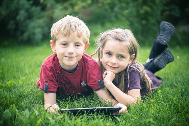 Portrait of brother and sister lying on a meadow with digital tablet model released Symbolfoto  SARF000868