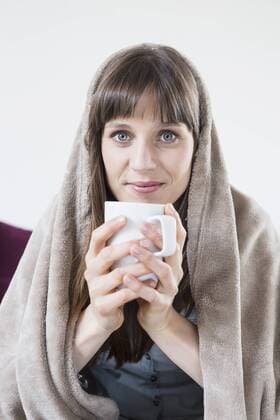 Portrait of mid adult woman covered with blanket and holding cup of tee mit_2002_03214