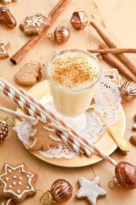 Ein Glas Eierpunsch mit Zimt und Weihnachtsdekoration  1079701655