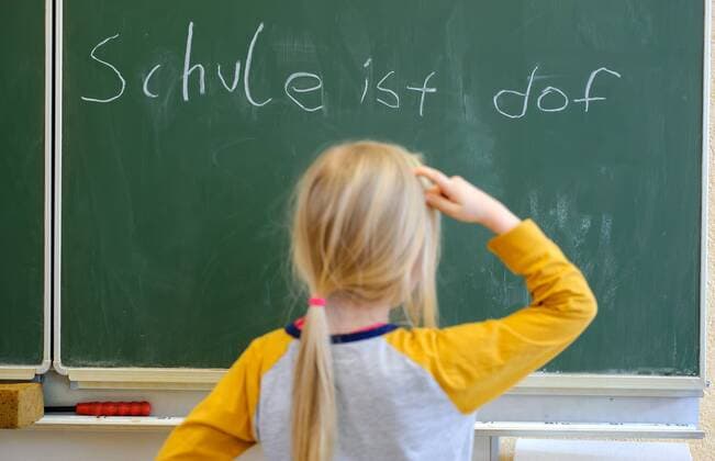 Ein Schulkind steht nachdenklich vor einer Schultafel, auf welcher Schule ist dof steht, aufgenommen am 19.01.2015 in Dresden.