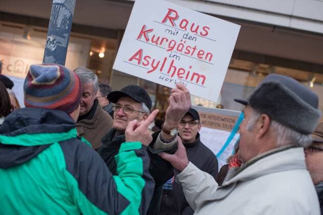 Hoyerswerda Rechte Pegida Hoygida Etwa 150 Anhaenger der sogenannten Hoygida, ein Ableger rechten Pegida-Bewegung im saechsischen Hoyerswerda, versammelten sich am Samstag den 24. Januar 2015 in der Kleinstadt zu einer Demonstration gegen eine angebliche Islamisierung Deutschlands. Etwa 100 der Veranstaltungsteilnehmer waren militante Neonazis und Hooligans aus Sachsen und Brandenburg. Im Bild: Ein Rechter hat sich unter die ca 100 Gegendemonstranten gemischt und provoziert sie mit einem selbstgemalten Schild Raus mit den Kurgaesten im Asylantenheim HoyWoi (fuer Hoyerswerda) . 24.1.2015, Hoyerswerda