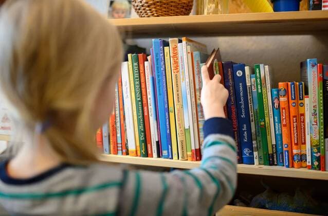 Ein Kind nimmt ein Buch aus seinem Bücherregal, aufgenommen am 28.01.2015.
