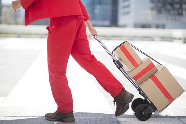 Red dressed parcel deliveryman with parcels model released Symbolfoto  ZEF002106
