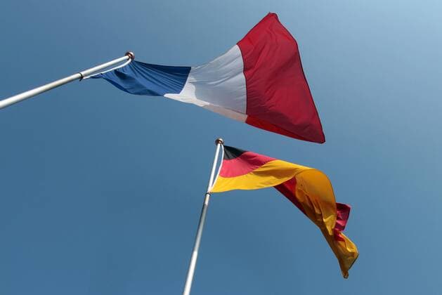 Flaggen Deutschland s und Frankreich s wehen eintraechtig vor blauem Himmel und Sonnenschein im Wind, Weil am Rhein, Baden-Wuerttemberg, Deutschland