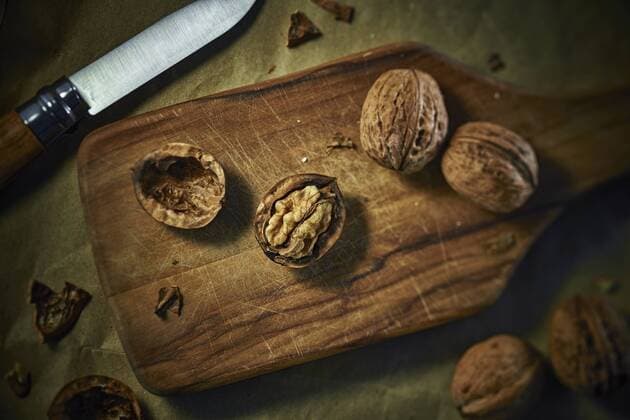 Cracked and whole walnuts on wooden board  DIKF000135
