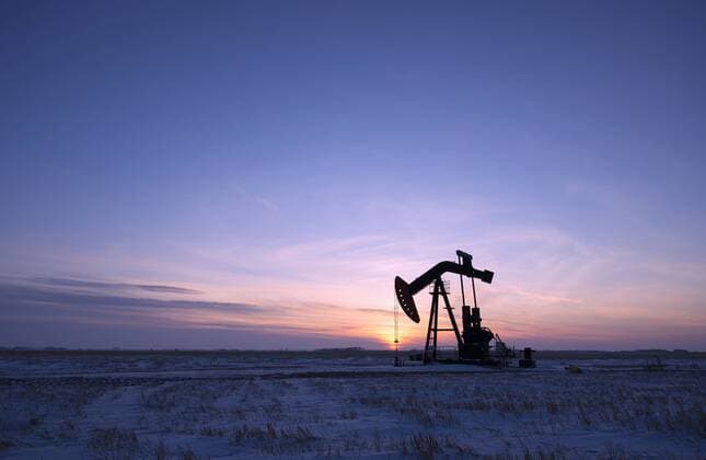 IMAGO Nature: Unsere Erde, Ressourcen, Erdöl An oil drilling rig and pumpjack on a flat plain in the Canadian oil fields at sunset.  15670