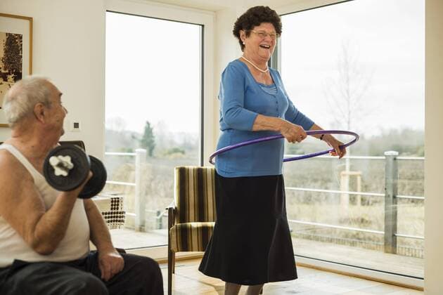 IMAGO Creative: Sport - Trend 2022: Hula Hoop Senior man with dumbbell and his wife with hula-hoop at home model released Symbolfoto property released  UUF003606