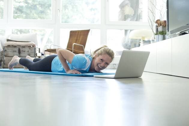 Woman with laptop exercising on gym mat in living room model released Symbolfoto property released  MAEF010090