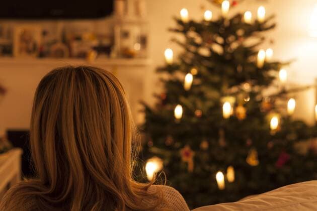 woman sitting on sofa with christmas tree