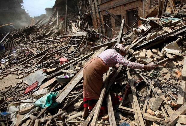 A Nepalese woman searches in the rubble of her collapsed house for her family members one day after an earthquake in Bhaktapur, Nepal April 26, 2015. New tremors sent shocked survivors scurrying outdoors just 24 hours after a devastating 7.9 magnitude earthquake shook the region which so far has taken the lives many, Nepalese officials said.  NEP2015042624 SANJOGxMANANDHAR