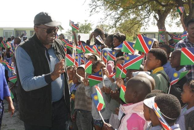 Namibian President Hage Geingob (L) gestures to children upon his arrival in the northern town of Tsumkwe in Namibia, May 22, 2015. Hage Geingob visited the north eastern section of the country on Friday. ) NAMIBIA-TSUMKWE-PRESIDENT-VISIT Nampa 