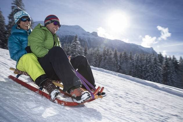 Germany, Bavaria, Inzell, couple having fun on a sledge in snow-covered landscape model released Symbolfoto  FFF001440