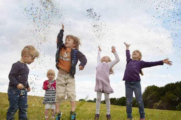 Five little children throwing confetti on a meadow model released Symbolfoto  STKF001355