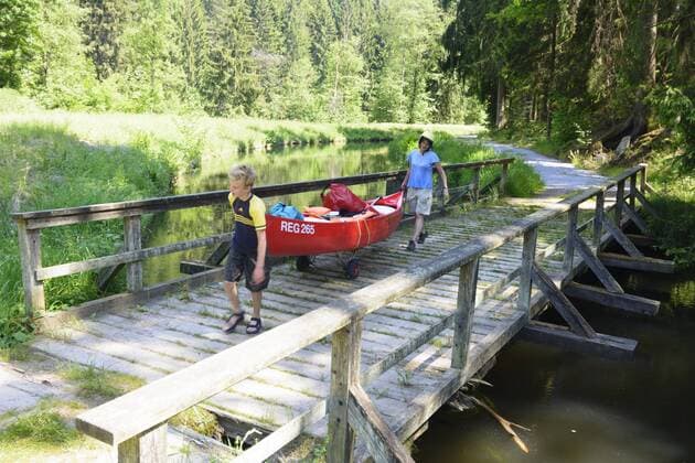Paddler beim Umtragen eines Kanu (Kanadier) an der Papierfabrik Pfleiderer auf dem Schwarzer Regen in Teisnach, Niederbayern, Bayern, Deutschland model released