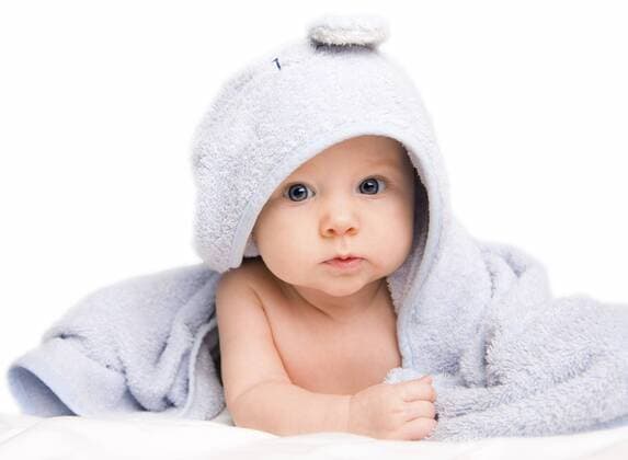 kleines niedliches Baby liegt in einem Badehandtuch eingewickelt auf dem Boden Cute baby girl with towel after bath BLWS233199
