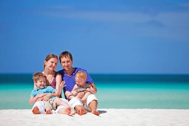 eine Familie mit zwei Kindern sitzt am tropischen Strand a family with two children sitting on tropical beach BLWS269830