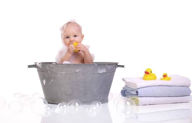 kleines Baby sitzt in einer Waschschuessel und badet mit einer Quietscheente Bath Time. Cute happy baby girl having bath BLWS233204
