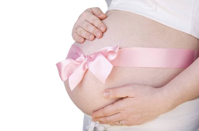 nackter Bauch einer schwangeren Frau, mit einer Schleife verziert pregnant belly with pink bow over it BLWS234332