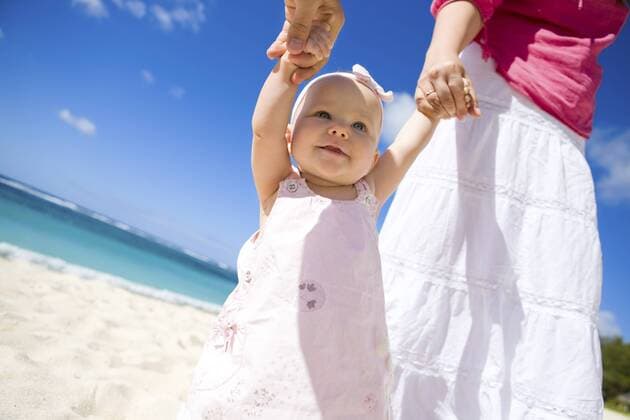 Eltern mit ihre Baby an der Hand am Sandstrand Young family with baby girl on white sand beach BLWS238330