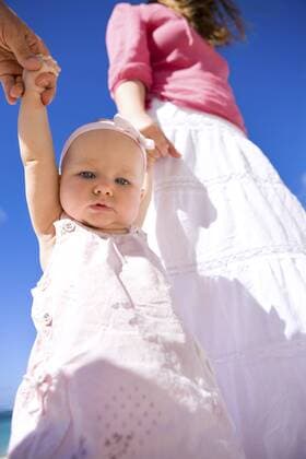 Eltern mit ihre Baby an der Hand am Sandstrand Young family with baby girl on white sand beach BLWS238331